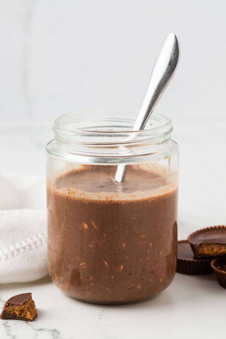Chocolate peanut butter overnight oats stirred in a glass jar.